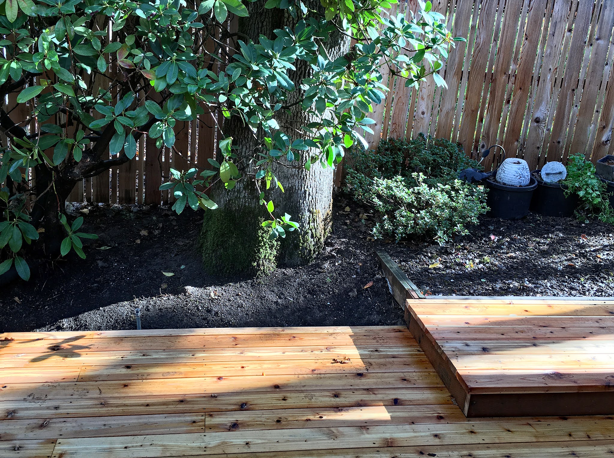 New cedar deck boards installed against a garden bed