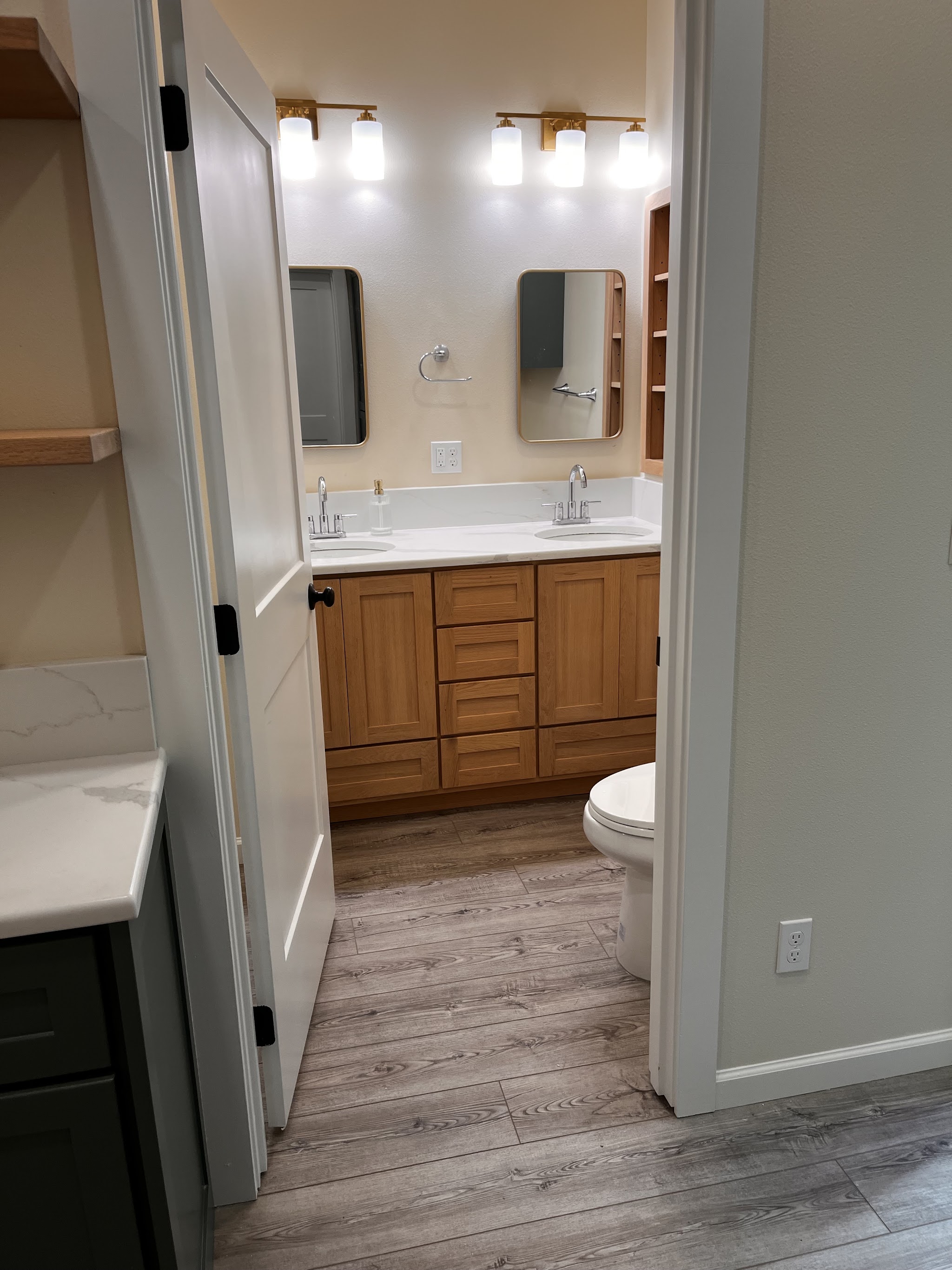 Finished double-vanity bathroom remodel with gold fixtures and oak cabinetry
